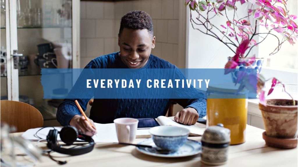 Person painting at a desk, expressing creativity through art in daily life